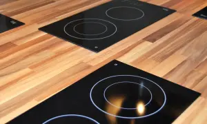 Plaques de cuisson modernes sur un plan de travail en bois. L'une est une plaque à induction ou vitrocéramique avec des cercles blancs.