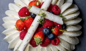 Pavlova aux fruits rouges, décorée de meringues fines et de feuilles d'or. Un délice visuel et gustatif.
