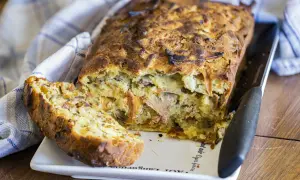 Un cake aux fanes de carottes, doré et moelleux, avec une tranche coupée, prêt à être dégusté.