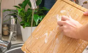 Nettoyer une planche à découper en bois avec du bicarbonate de soude et de l'eau savonneuse sous le robinet.