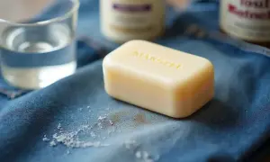 Une tache sur pantalon de jean, avec du savon et du bicarbonate de soude pour la nettoyer.