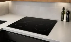 Plaque de cuisson à induction moderne, quatre zones, intégrée dans un plan de travail clair. Un poêle induction sur gaz, prêt pour des repas savoureux.