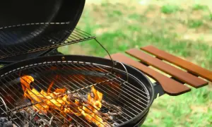 Le barbecue à charbon chauffe, les flammes dansent sur les braises. La température monte pour un repas d'été parfait.