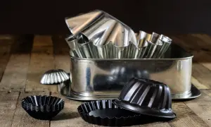Un assortiment de moules à pâtisserie en acier, certains brillants, d'autres noirs. Attention, le moule en acier peut être dangereux si mal utilisé.