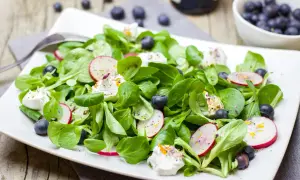Salade verte fraîche avec radis, myrtilles et fromage frais. Une idée de quoi mettre dans une salade verte pour un repas léger et coloré.