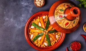 Un plat de couscous coloré avec des carottes, courgettes et pois chiches. Les légumes pour le couscous sont disposés en étoile sur le grain.