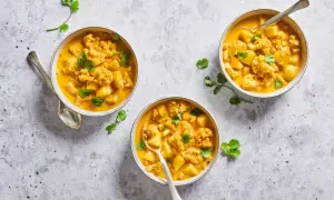 Trois bols de chou-fleur curry crémeux, garni de coriandre fraîche. Un plat réconfortant et savoureux.