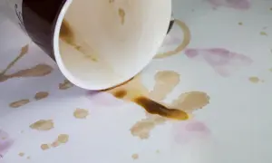Tasses renversées sur une nappe blanche, laissant des taches de café et de vin. Comment enlever taches anciennes sur nappe blanche ?