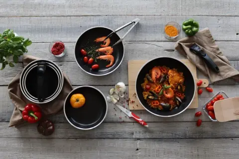 Préparation d'une paella savoureuse dans une poêle au meilleur revêtement. Ingrédients frais et ustensiles de cuisine de qualité.