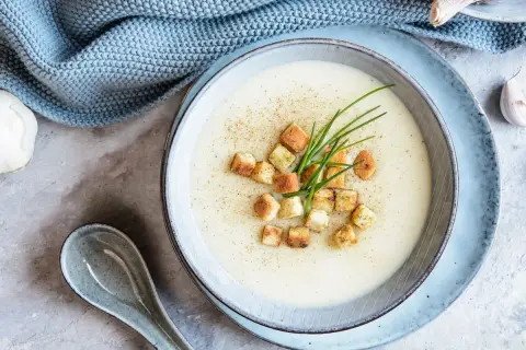Délicieuse soupe de mache crémeuse, garnie de croûtons dorés et de ciboulette fraîche. Une touche de poivre pour parfaire ce plat réconfortant.