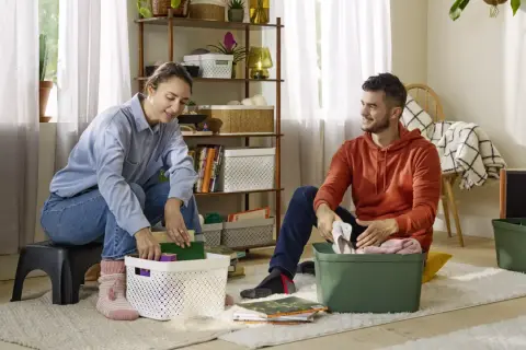 Couple rangeant des objets dans des boîtes, une étape pour vider sa maison pour alléger sa vie.