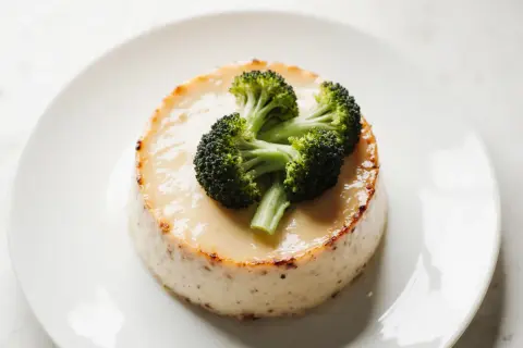 Un flan de brocolis, crémeux et doré, est garni de quelques fleurettes de brocolis frais.