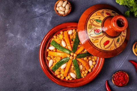 Un plat de couscous coloré avec des carottes, courgettes et pois chiches. Les légumes pour le couscous sont disposés en étoile sur le grain.