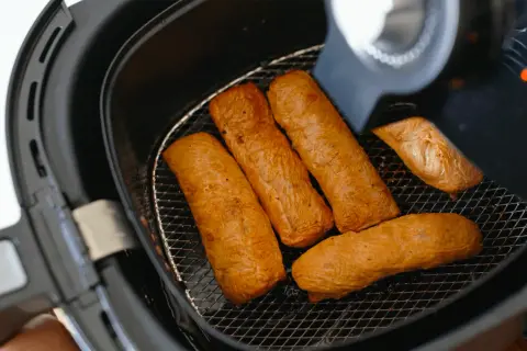 Cinq saucisses dorées dans une friteuse sans huile. Découvrez comment ça marche pour des repas sains et croustillants !