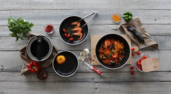 Préparation d'une paella savoureuse dans une poêle au meilleur revêtement. Ingrédients frais et ustensiles de cuisine de qualité.