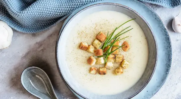 Délicieuse soupe de mache crémeuse, garnie de croûtons dorés et de ciboulette fraîche. Une touche de poivre pour parfaire ce plat réconfortant.
