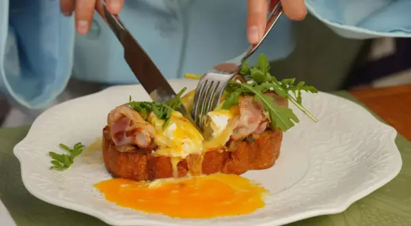 Un délicieux pain perdu salé avec œuf poché coulant, bacon croustillant et roquette fraîche.