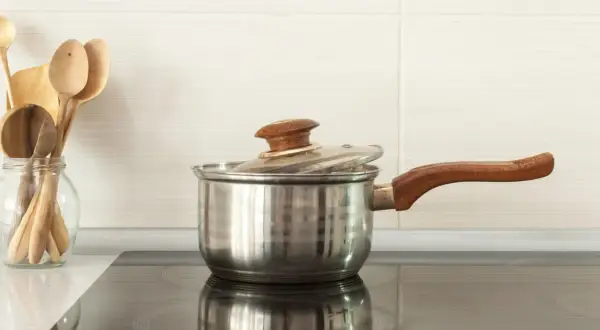 Une casserole en inox sur une plaque à induction. Pour savoir si une casserole est compatible induction, vérifiez le fond.