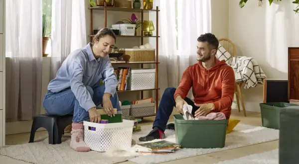 Couple rangeant des objets dans des boîtes, une étape pour vider sa maison pour alléger sa vie.
