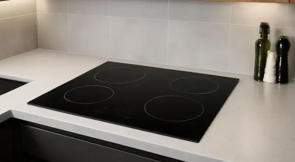 Plaque de cuisson à induction moderne, quatre zones, intégrée dans un plan de travail clair. Un poêle induction sur gaz, prêt pour des repas savoureux.