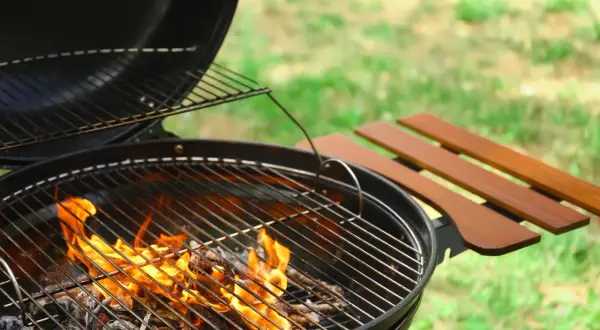 Le barbecue à charbon chauffe, les flammes dansent sur les braises. La température monte pour un repas d'été parfait.