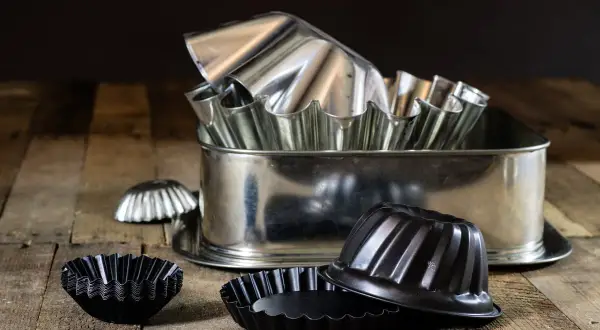 Un assortiment de moules à pâtisserie en acier, certains brillants, d'autres noirs. Attention, le moule en acier peut être dangereux si mal utilisé.