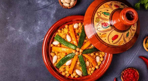 Un plat de couscous coloré avec des carottes, courgettes et pois chiches. Les légumes pour le couscous sont disposés en étoile sur le grain.