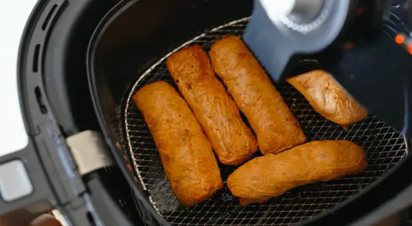 Cinq saucisses dorées dans une friteuse sans huile. Découvrez comment ça marche pour des repas sains et croustillants !