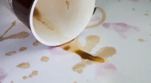 Tasses renversées sur une nappe blanche, laissant des taches de café et de vin. Comment enlever taches anciennes sur nappe blanche ?