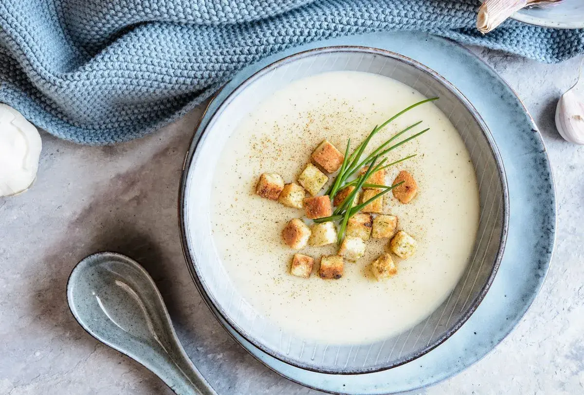 Délicieuse soupe de mache crémeuse, garnie de croûtons dorés et de ciboulette fraîche. Une touche de poivre pour parfaire ce plat réconfortant.