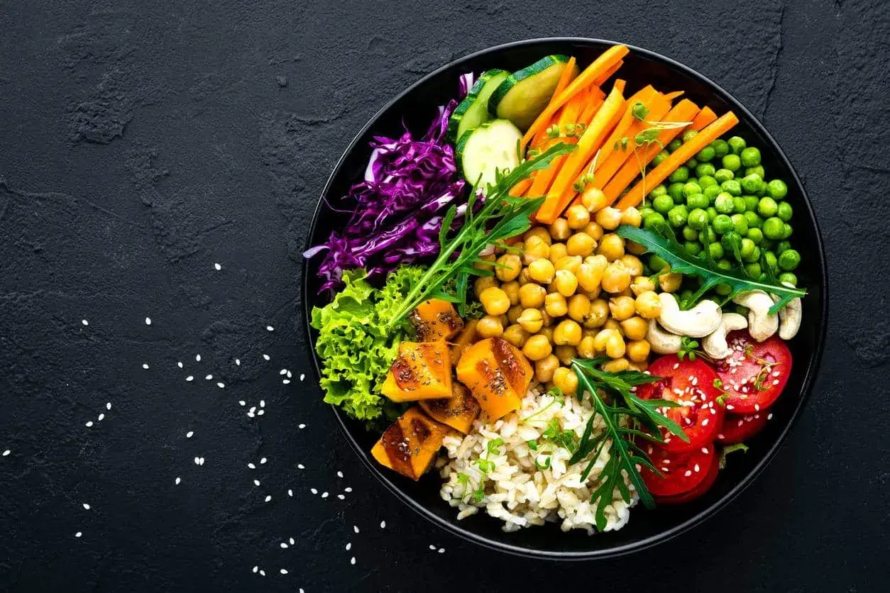 Un bol coloré avec riz, pois chiches, carottes, tomates, courge, chou rouge, laitue et pois. Un plat sain et savoureux, plein de legume en f.