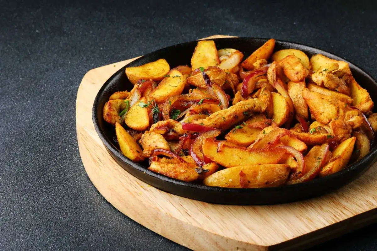 Plat chaud de poulet et pommes de terre coup&eacute;es en quartiers, avec des oignons rouges, pr&ecirc;t pour la cuisson.