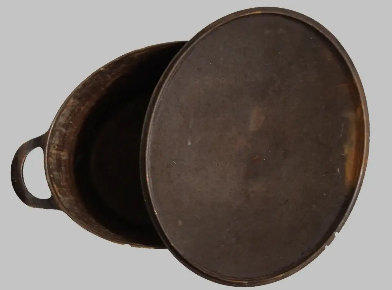 Une cocotte en fonte ouverte, pr&ecirc;te pour son entretien. Sa surface patin&eacute;e t&eacute;moigne de son histoire culinaire.