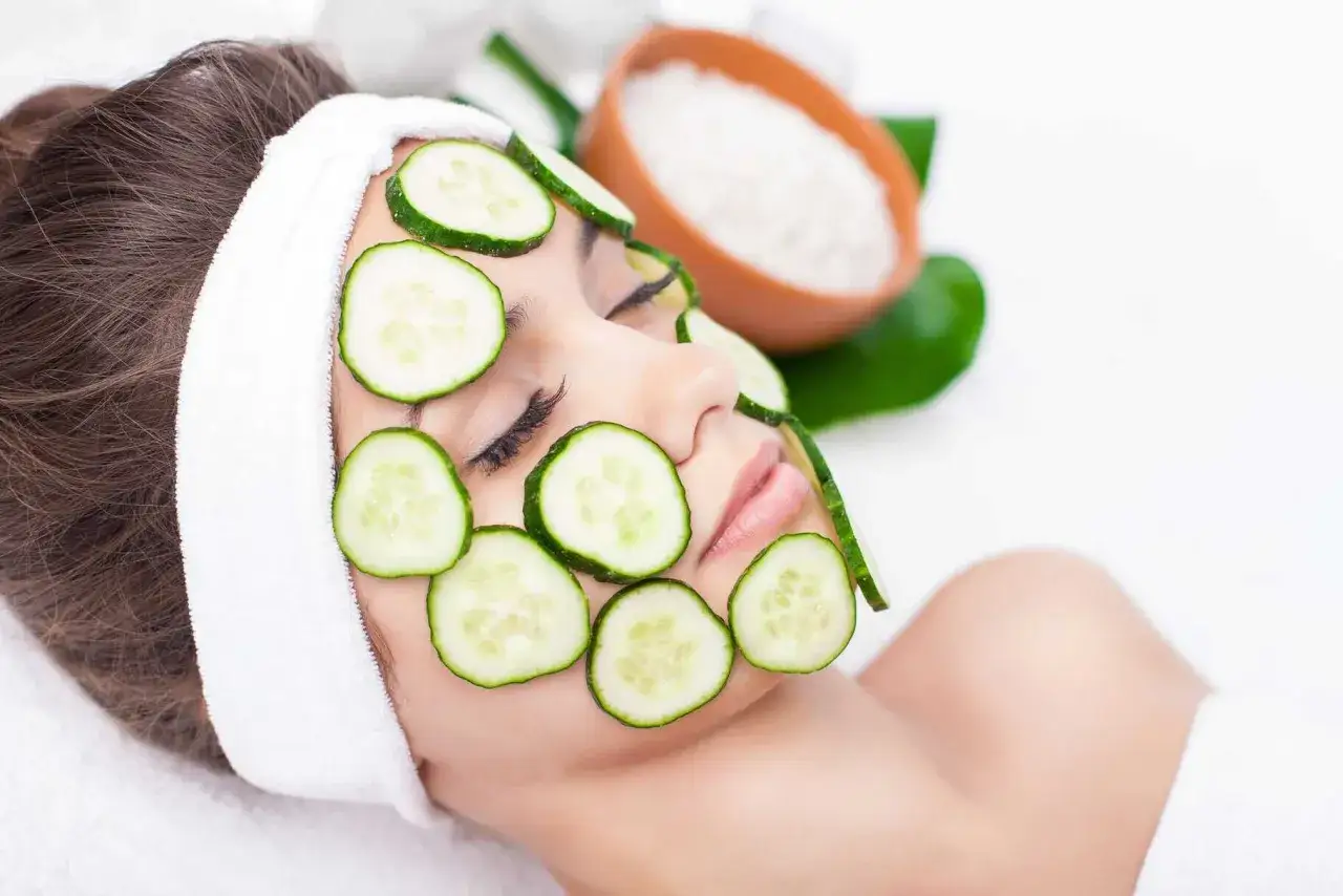 Une femme au visage couvert de rondelles de concombre, une astuce beaut&eacute; pour savoir s'il faut &eacute;plucher un concombre pour un soin.