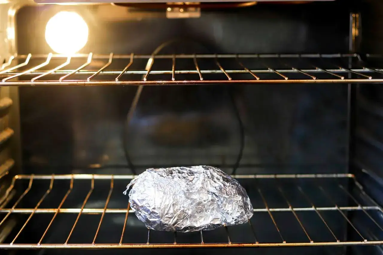 Un aliment envelopp&eacute; dans du papier aluminium est plac&eacute; sur une grille dans un four allum&eacute;. Est-ce que l'aluminium va au four ? Oui, il est couramment utilis&eacute; pour la cuisson.