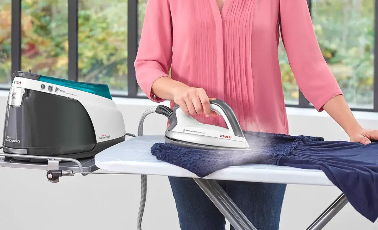 Une personne utilise un fer &agrave; repasser &agrave; vapeur sur une planche. La vapeur s'&eacute;chappe, indiquant une temp&eacute;rature de fer &agrave; repasser id&eacute;ale pour d&eacute;froisser le tissu.