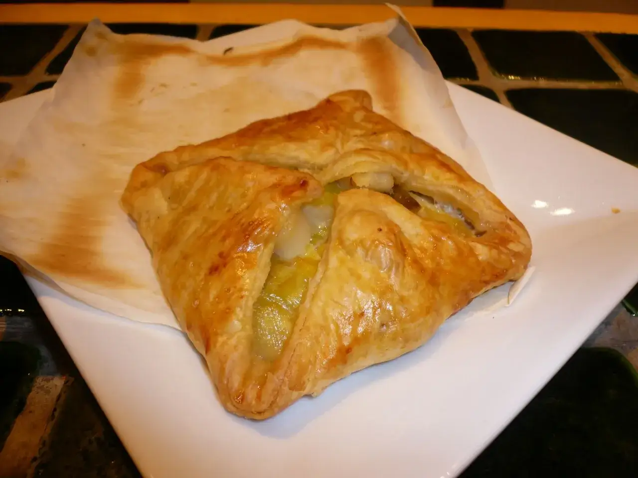 Un feuillet&eacute; dor&eacute; aux Saint-Jacques et poireaux, servi sur une assiette blanche.