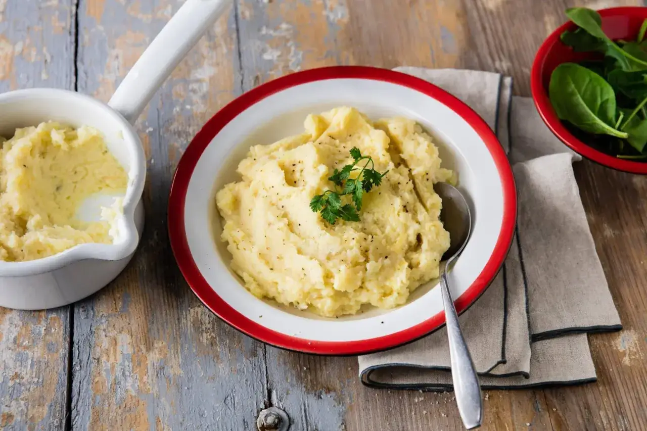 Une assiette de pur&eacute;e celeri pomme de terre onctueuse, garnie de persil frais et poivr&eacute;e, servie avec une petite coupelle de jeunes pousses d'&eacute;pinards.