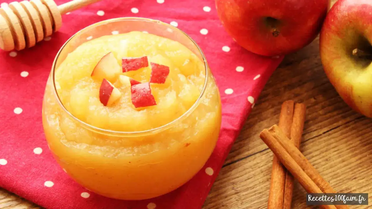 Un verre de compote de pomme maison, garni de d&eacute;s de pommes rouges, sur un fond de serviette &agrave; pois rouges, avec des pommes et des b&acirc;tons de cannelle.