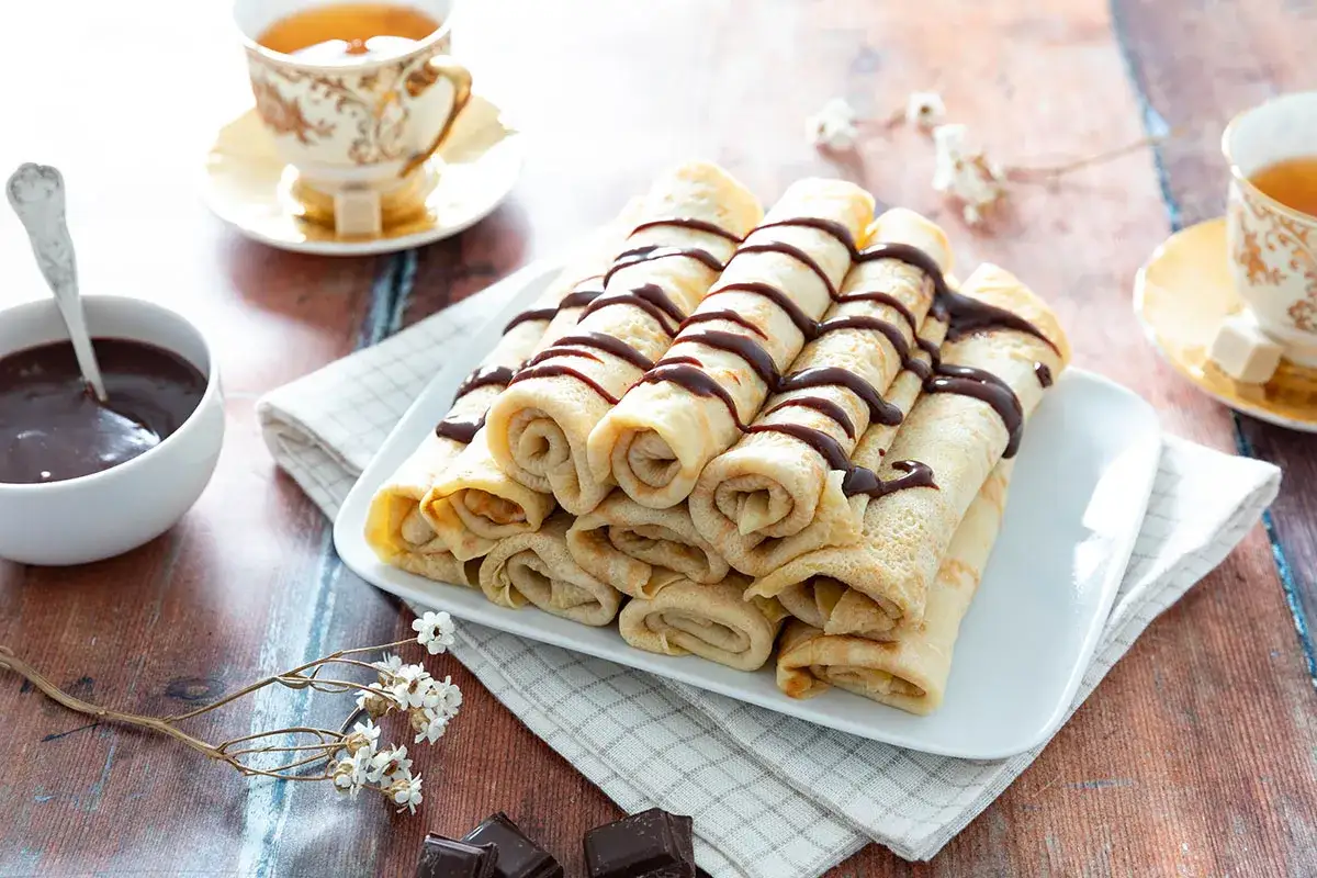 Cr&ecirc;pes roul&eacute;es et napp&eacute;es de chocolat, pr&ecirc;tes pour la d&eacute;gustation. La pr&eacute;paration de la p&acirc;te &agrave; cr&ecirc;pes est termin&eacute;e, place au plaisir !