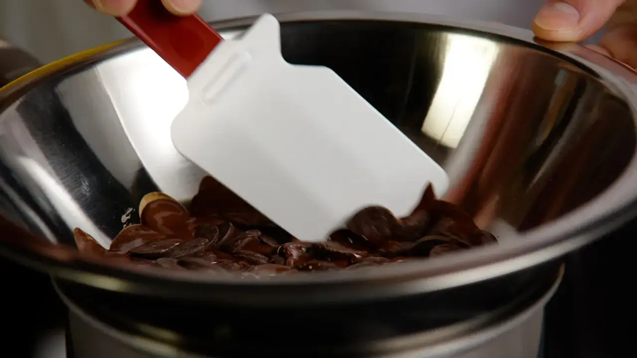Chocolat fondant dans un bol au-dessus d'un bain-marie eau chaude ou froide, m&eacute;lang&eacute; avec une spatule.