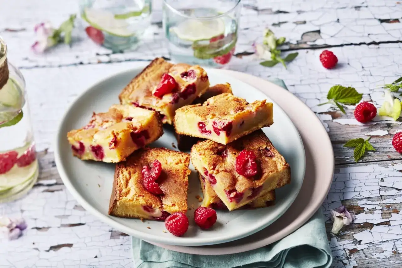 Carr&eacute;s gourmands de brownie chocolat blanc framboise, parsem&eacute;s de fruits rouges frais sur une assiette claire.