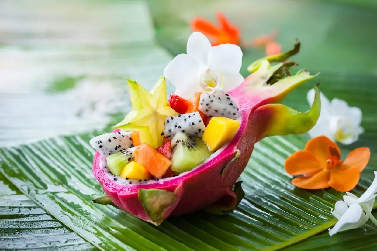 Salade de fruits exotiques color&eacute;e servie dans une demi-pitaya, avec des &eacute;toiles de carambole, des morceaux de kiwi, mangue et fraise. Un fruit en y, plein de saveurs.