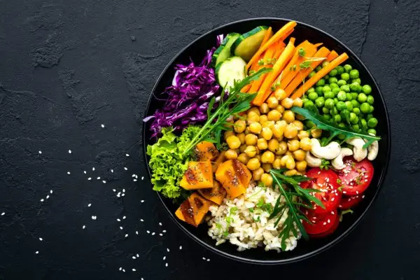 Un bol coloré avec riz, pois chiches, carottes, tomates, courge, chou rouge, laitue et pois. Un plat sain et savoureux, plein de legume en f.