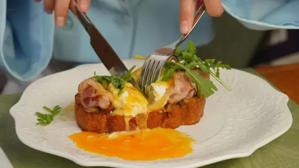 Un délicieux pain perdu salé avec œuf poché coulant, bacon croustillant et roquette fraîche.