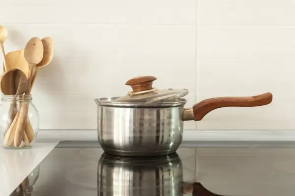 Une casserole en inox sur une plaque à induction. Pour savoir si une casserole est compatible induction, vérifiez le fond.
