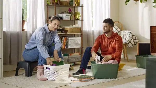 Couple rangeant des objets dans des boîtes, une étape pour vider sa maison pour alléger sa vie.