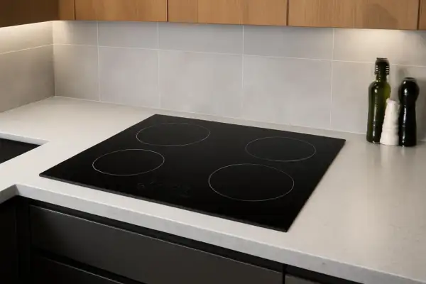 Plaque de cuisson à induction moderne, quatre zones, intégrée dans un plan de travail clair. Un poêle induction sur gaz, prêt pour des repas savoureux.