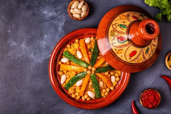 Un plat de couscous coloré avec des carottes, courgettes et pois chiches. Les légumes pour le couscous sont disposés en étoile sur le grain.