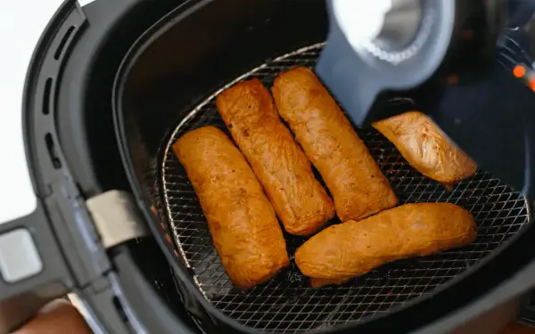 Cinq saucisses dorées dans une friteuse sans huile. Découvrez comment ça marche pour des repas sains et croustillants !